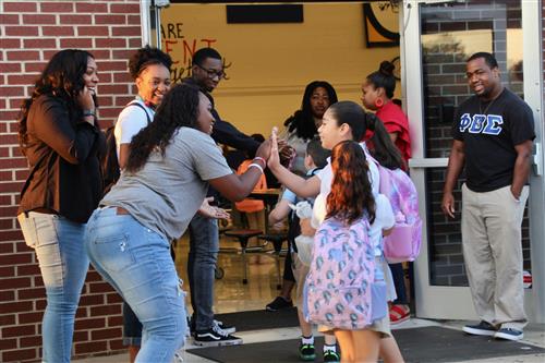 Staff high-fiving students as they enter building